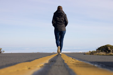 Woman walking down the street above the clouds at Haleakala National Park on the Hawaiian Island of...