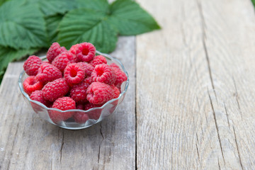red raspberries in bowl on wooden background