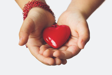 Red heart pendant on little girl's palms of hands