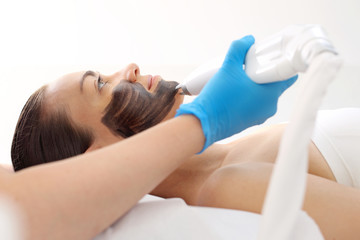 Maseczka z węglem aktywnym. Kobieta w gabinecie kosmetycznym podczas zabiegu pielęgnacyjnego na skórę twarzy.