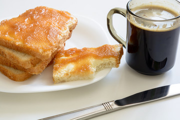 Tasty breakfast. Toasts with butter and jam on a plate. Cup of coffe.
