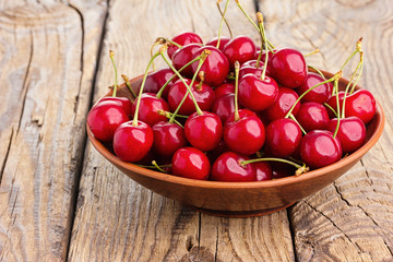 Fresh cherry in bowl on wooden background.