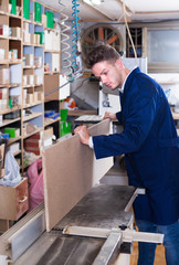 Young male woodworker adjusting chipboard