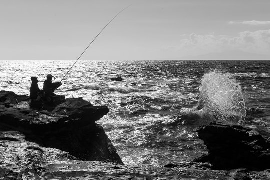 Silhouette of people fishing at the Jogoshima island in Japan during the sunny day black and white picture