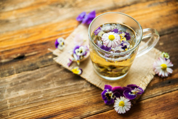 Fototapeta na wymiar Cup of tea with chamomile flowers on rustic wooden background