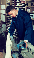 male worker processing plank in machine at workshop