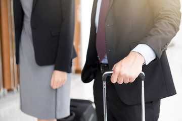 Business people holding luggage, walking in airport terminal