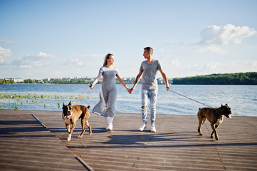 Couple in love with two dogs pit bull terrier against beach side.