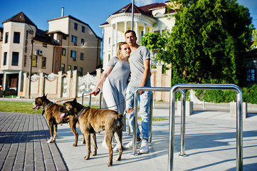 Couple in love with two dogs pit bull terrier on a walk.