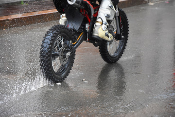 From the wheels of a motorcycle under heavy rain there are strong sprays
