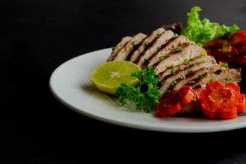 Sliced chicken breast barbecue on white plate served with grilled vegetable. Delicious  chicken breast steak and salad for dinner. Homemade chicken breast barbecue on granite table for background.