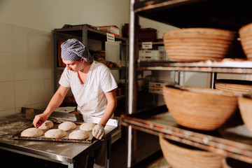 a Baker makes manual incisions on the dough for the bread. The Manufacture Of Bread.Bakery