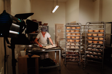 Baker kneading dough and forming loaf of bread