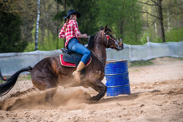 A barrel racer at a rodeo makes an explosive turn around one of the barrels, sending arena sand...