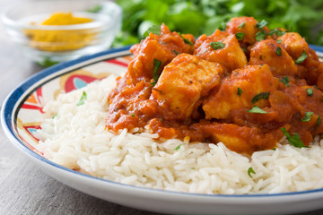 Chicken tikka masala with basmati rice on wooden table
