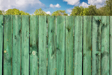 Fototapeta premium Old wooden turquoise fence and blue sky with clouds