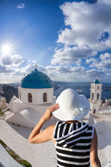 Woman with hat watching famous church on Santorini island in Greece
