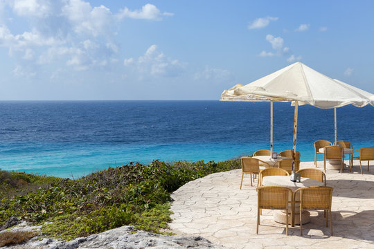 Terrace with the most amazing view. The Caribbean sea surrounding the table area on the beach. Tables composed to the right. Relaxation and vacation concept image.