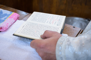 The priest holds the Bible at the altar, church utensil, the Bible on the table, ceremony of water baptism christening
