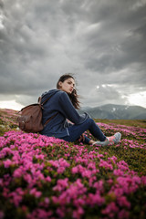Naklejka na ściany i meble Flowers in the mountains. Shot of a young woman looking at the landscape while hiking in the mountains. Magic pink rhododendron flowers on summer mountain