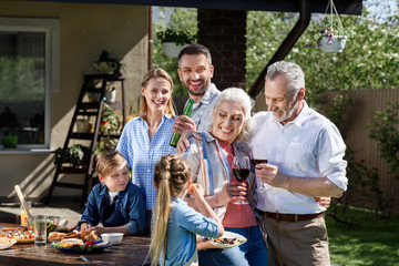 Portrait of smiling multi-generational family having picnic on patio at daytime
