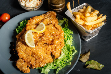 details of delicious dinner - french fries and coleslaw with parmesan grilled schnitzel