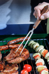 cropped shot of human hand pricking roasted steak with barbecue fork