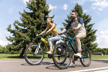 Obraz premium young casual couple riding on bicycles in park at daytime