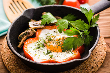 Fried eggs in pepper, parsley and mushrooms in the iron pan