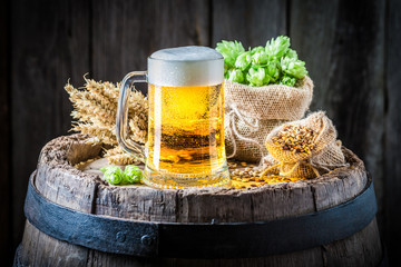 Light beer with foam, hops and wheat on barrel
