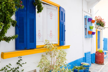Traditional Greek facade of house with blue colours accents of window and door.
