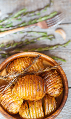 Baked potatoes with rosemary in a wooden bowl.