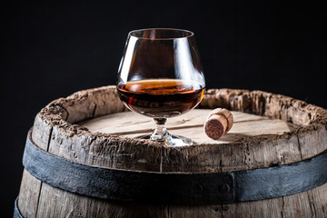 Glass of good whisky on oak barrel