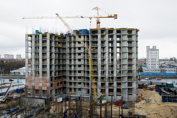 View of the construction site on which a multi-storey house is built and machinery and people work