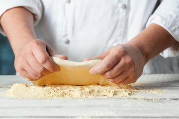 Closeup hand of chef baker in white uniform making pizza at kitchen