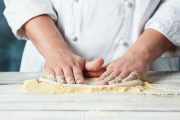 Closeup hand of chef baker in white uniform making pizza at kitchen