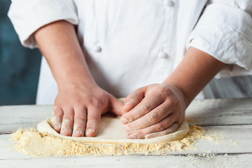 Closeup hand of chef baker in white uniform making pizza at kitchen