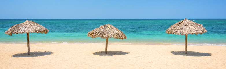 Straw umbrellas on a beautiful tropical beach, panoramic travel background, travel and tourism concept