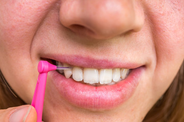 Naklejka premium Woman brushing her teeth with interdental brush