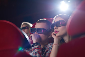 Close up shot of a young couple wearing 3D glasses watching a movie at the local cinema technology modern realistic entertainment activity concept.