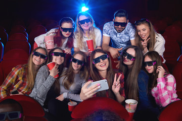 Happy young girl taking a selfie with a group of her friends at the cinema people wearing 3D glasses happiness positivity entertaining activity leisure togetherness celebration unity diversity.