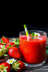 Strawberry smoothie and strawberries on wooden background