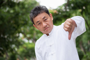 asian kung fu senior man showing thumb down hand gesture