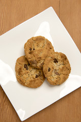 Three chocolate chip cookies on a white plate 