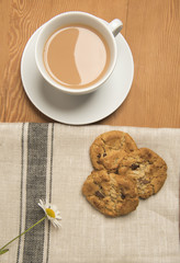 Tea with chocolate chip cookies and a single flower 