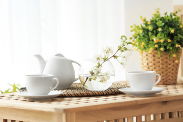 Tea set and vase with beautiful flowers on wooden table