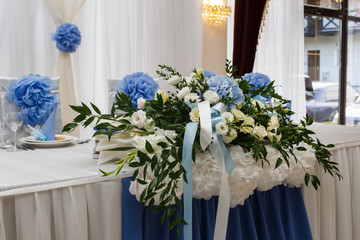 Blue hydrangeas and white roses decorate dinner table for newlyweds