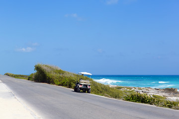 Rental car parked on the side of the road next to a sea. Beautiful view on the spot. The car is a buggy for tourists.