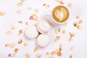 Fototapeta na wymiar Fresh, cream-colored macaroons with coffee on a white background