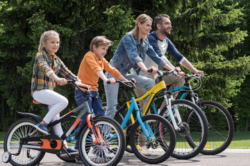 Obraz premium side view of happy family riding bicycles while spending time together in park